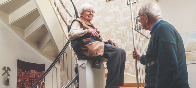 Eine ältere Damen fährt mit einem Sitzlift